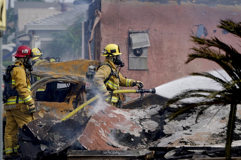 kecelakaan pesawat di Santee, California, AS Fire crews work the scene of a small plane crash, Monday, Oct. 11, 2021, in Santee, Calif. At least two people were killed and two others were injured when the plane crashed into a suburban Southern California neighborhood, setting two homes ablaze, authorities said. (AP Photo/Gregory Bull)