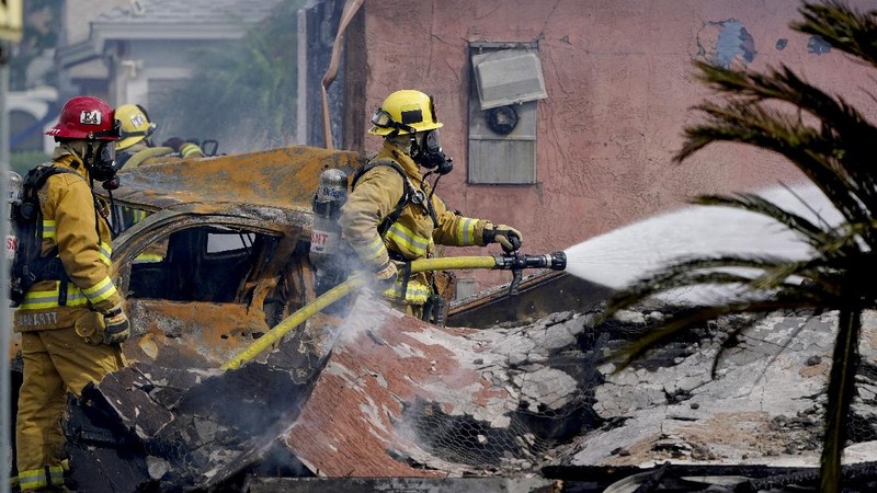 Fire crews work the scene of a small plane crash, Monday, Oct. 11, 2021, in Santee, Calif. At least two people were killed and two others were injured when the plane crashed into a suburban Southern California neighborhood, setting two homes ablaze, authorities said. (AP Photo/Gregory Bull)