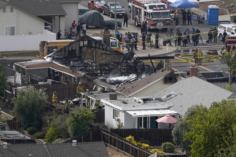 kecelakaan pesawat di Santee, California, AS Fire crews work the scene of a small plane crash, Monday, Oct. 11, 2021, in Santee, Calif. At least two people were killed and two others were injured when the plane crashed into a suburban Southern California neighborhood, setting two homes ablaze, authorities said. (AP Photo/Gregory Bull)