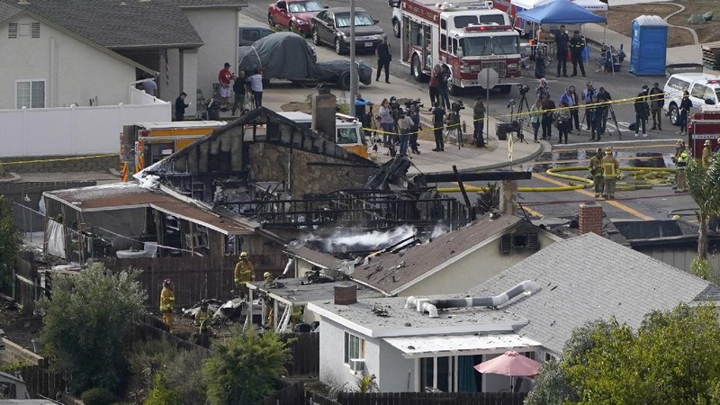 Fire crews work the scene of a small plane crash, Monday, Oct. 11, 2021, in Santee, Calif. At least two people were killed and two others were injured when the plane crashed into a suburban Southern California neighborhood, setting two homes ablaze, authorities said. (AP Photo/Gregory Bull)