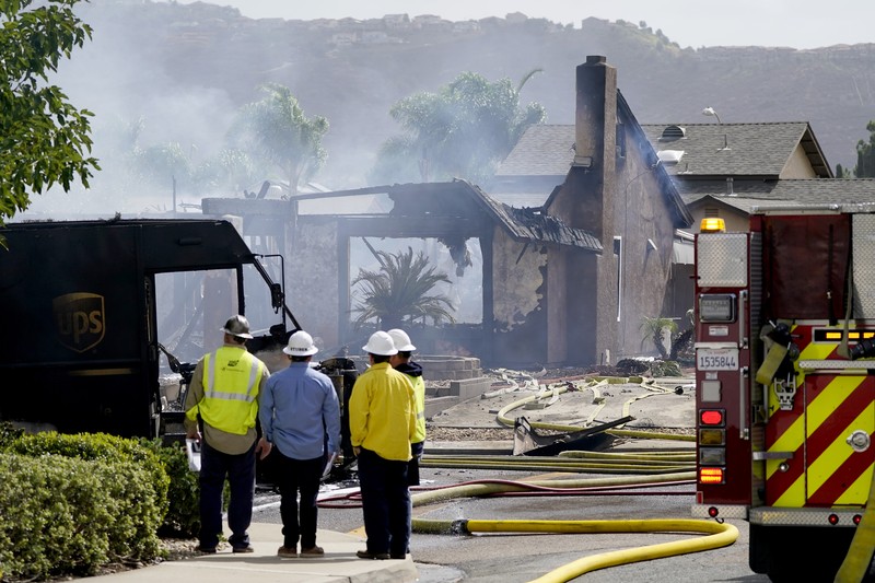 kecelakaan pesawat di Santee, California, AS Fire crews work the scene of a small plane crash, Monday, Oct. 11, 2021, in Santee, Calif. At least two people were killed and two others were injured when the plane crashed into a suburban Southern California neighborhood, setting two homes ablaze, authorities said. (AP Photo/Gregory Bull)