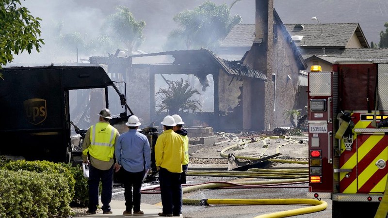 Fire crews work the scene of a small plane crash, Monday, Oct. 11, 2021, in Santee, Calif. At least two people were killed and two others were injured when the plane crashed into a suburban Southern California neighborhood, setting two homes ablaze, authorities said. (AP Photo/Gregory Bull)