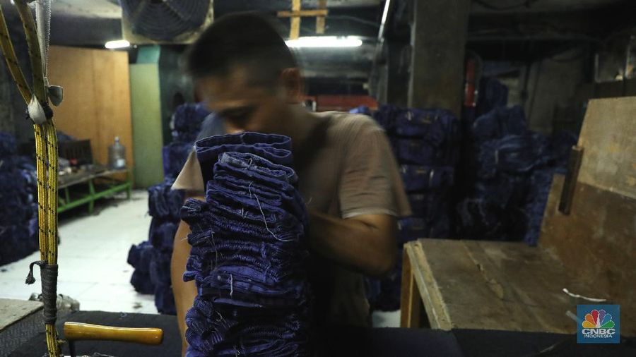 Pekerja menyelesaikan proses pewarnaan dan pencucian pakaian di salah satu pabrik dikawasan Jakarta, Selasa (11/10/2021). Industri tekstil dan produksi tekstil (TPT) mengalami pasang surut sejak pandemi Covid-19 sejak beberapa tahun belakangan. Setelah sebelumnya berhasil bangkit kembali pada kuartal IV 2020, Pemberlakuan Pembatasan Kegiatan Masyarakat (PPKM) mikro pada tahun ini kembali bergeliat. Kontribusi penurunan terbesar berasal dari penurunan pakaian jadi yang memiliki porsi 66% dari total ekspor TPT Indonesia. Tekanan terhadap industri TPT setidaknya masih terjadi hingga paruh pertama 2021. Kinerja TPT sedikit terbantu oleh adanya permintaan Alat Pelindung Diri atau APD untuk keperluan penanganan COVID-19. Namun permintaan terhadap APD tersebut tidak cukup besar untuk menutupi turunnya penjualan produk produk TPT secara keseluruhan. Menurut owner Helmi 