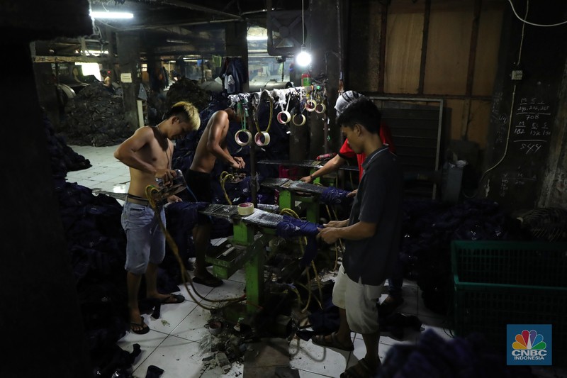 Pekerja menyelesaikan proses pewarnaan dan pencucian pakaian di salah satu pabrik dikawasan Jakarta, Selasa (11/10/2021). Industri tekstil dan produksi tekstil (TPT) mengalami pasang surut sejak pandemi Covid-19 sejak beberapa tahun belakangan. Setelah sebelumnya berhasil bangkit kembali pada kuartal IV 2020, Pemberlakuan Pembatasan Kegiatan Masyarakat (PPKM) mikro pada tahun ini kembali bergeliat. Kontribusi penurunan terbesar berasal dari penurunan pakaian jadi yang memiliki porsi 66% dari total ekspor TPT Indonesia. Tekanan terhadap industri TPT setidaknya masih terjadi hingga paruh pertama 2021. Kinerja TPT sedikit terbantu oleh adanya permintaan Alat Pelindung Diri atau APD untuk keperluan penanganan COVID-19. Namun permintaan terhadap APD tersebut tidak cukup besar untuk menutupi turunnya penjualan produk produk TPT secara keseluruhan. Menurut owner Helmi 