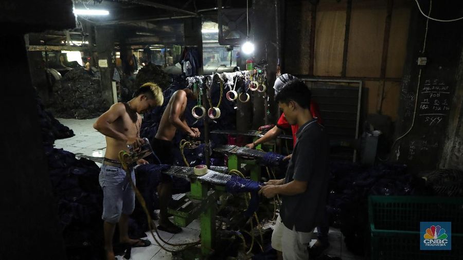Pekerja menyelesaikan proses pewarnaan dan pencucian pakaian di salah satu pabrik dikawasan Jakarta, Selasa (11/10/2021). Industri tekstil dan produksi tekstil (TPT) mengalami pasang surut sejak pandemi Covid-19 sejak beberapa tahun belakangan. Setelah sebelumnya berhasil bangkit kembali pada kuartal IV 2020, Pemberlakuan Pembatasan Kegiatan Masyarakat (PPKM) mikro pada tahun ini kembali bergeliat. Kontribusi penurunan terbesar berasal dari penurunan pakaian jadi yang memiliki porsi 66% dari total ekspor TPT Indonesia. Tekanan terhadap industri TPT setidaknya masih terjadi hingga paruh pertama 2021. Kinerja TPT sedikit terbantu oleh adanya permintaan Alat Pelindung Diri atau APD untuk keperluan penanganan COVID-19. Namun permintaan terhadap APD tersebut tidak cukup besar untuk menutupi turunnya penjualan produk produk TPT secara keseluruhan. Menurut owner Helmi 