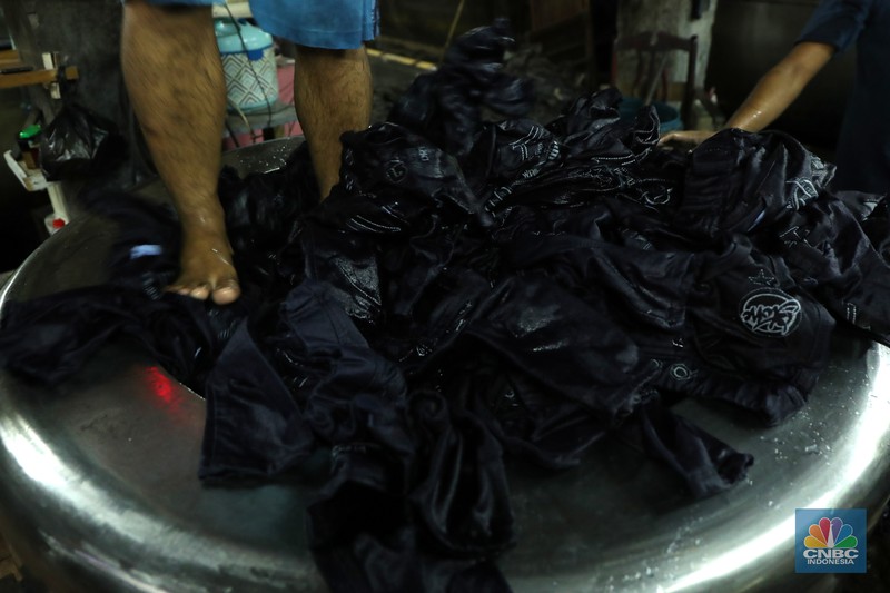 Pekerja menyelesaikan proses pewarnaan dan pencucian pakaian di salah satu pabrik dikawasan Jakarta, Selasa (11/10/2021). Industri tekstil dan produksi tekstil (TPT) mengalami pasang surut sejak pandemi Covid-19 sejak beberapa tahun belakangan. Setelah sebelumnya berhasil bangkit kembali pada kuartal IV 2020, Pemberlakuan Pembatasan Kegiatan Masyarakat (PPKM) mikro pada tahun ini kembali bergeliat. Kontribusi penurunan terbesar berasal dari penurunan pakaian jadi yang memiliki porsi 66% dari total ekspor TPT Indonesia. Tekanan terhadap industri TPT setidaknya masih terjadi hingga paruh pertama 2021. Kinerja TPT sedikit terbantu oleh adanya permintaan Alat Pelindung Diri atau APD untuk keperluan penanganan COVID-19. Namun permintaan terhadap APD tersebut tidak cukup besar untuk menutupi turunnya penjualan produk produk TPT secara keseluruhan. Menurut owner Helmi 