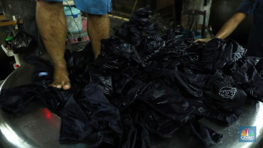 Pekerja menyelesaikan proses pewarnaan dan pencucian pakaian di salah satu pabrik dikawasan Jakarta, Selasa (11/10/2021). Industri tekstil dan produksi tekstil (TPT) mengalami pasang surut sejak pandemi Covid-19 sejak beberapa tahun belakangan. Setelah sebelumnya berhasil bangkit kembali pada kuartal IV 2020, Pemberlakuan Pembatasan Kegiatan Masyarakat (PPKM) mikro pada tahun ini kembali bergeliat. Kontribusi penurunan terbesar berasal dari penurunan pakaian jadi yang memiliki porsi 66% dari total ekspor TPT Indonesia. Tekanan terhadap industri TPT setidaknya masih terjadi hingga paruh pertama 2021. Kinerja TPT sedikit terbantu oleh adanya permintaan Alat Pelindung Diri atau APD untuk keperluan penanganan COVID-19. Namun permintaan terhadap APD tersebut tidak cukup besar untuk menutupi turunnya penjualan produk produk TPT secara keseluruhan. Menurut owner Helmi 