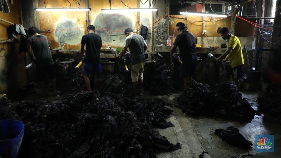 Pekerja menyelesaikan proses pewarnaan dan pencucian pakaian di salah satu pabrik dikawasan Jakarta, Selasa (11/10/2021). Industri tekstil dan produksi tekstil (TPT) mengalami pasang surut sejak pandemi Covid-19 sejak beberapa tahun belakangan. Setelah sebelumnya berhasil bangkit kembali pada kuartal IV 2020, Pemberlakuan Pembatasan Kegiatan Masyarakat (PPKM) mikro pada tahun ini kembali bergeliat. Kontribusi penurunan terbesar berasal dari penurunan pakaian jadi yang memiliki porsi 66% dari total ekspor TPT Indonesia. Tekanan terhadap industri TPT setidaknya masih terjadi hingga paruh pertama 2021. Kinerja TPT sedikit terbantu oleh adanya permintaan Alat Pelindung Diri atau APD untuk keperluan penanganan COVID-19. Namun permintaan terhadap APD tersebut tidak cukup besar untuk menutupi turunnya penjualan produk produk TPT secara keseluruhan. Menurut owner Helmi 