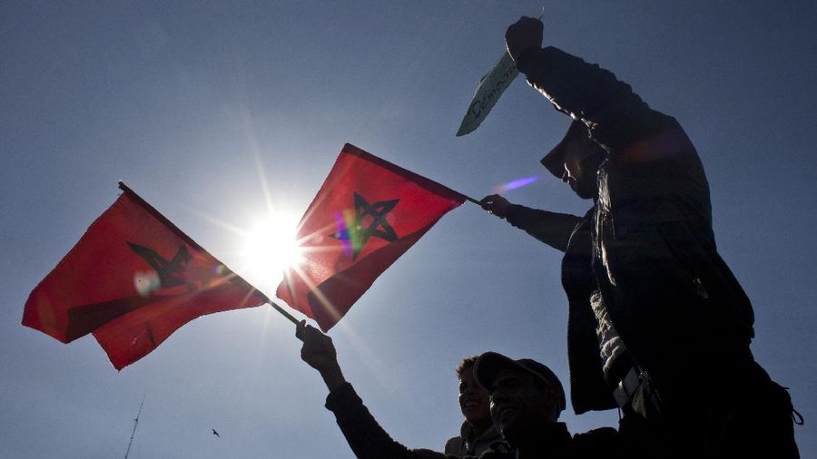 Protesters hold  the Moroccan flag   during a demonstration  in Casablanca, Morocco, Sunday Feb.20, 2011. Thousands of people marched in cities across Morocco on Sunday, demanding a new constitution to bring more democracy in the North African kingdom amid the wave of Arab world upheaval.  (AP Photo/Thibault Camus)