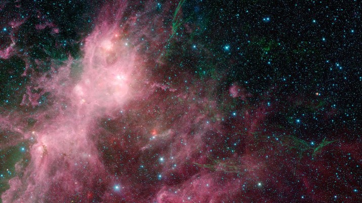 This image made available by NASA shows infrared data from the Spitzer Space Telescope and Wide-field Infrared Survey Explorer (WISE) in an area known as the W3 and W5 star-forming regions within the Milky Way Galaxy. The stringy, seaweed-like filaments are the blown out remnants of a star that exploded in a supernova. The billowy clouds seen in pink are sites of massive star formation. Clusters of massive stars can be seen lighting up the clouds, and a bubble carved out from massive stars is seen near the bottom. (NASA/JPL-Caltech/University of Wisconsin via AP)