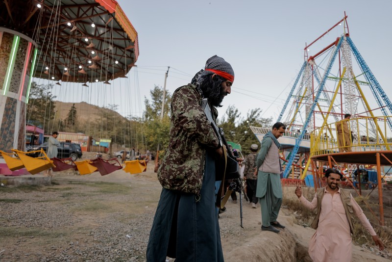 Pejuang Taliban Afghanistan cuti liburan rekreasi Taliban fighters get out of a vehicle as they take a day off to visit the amusement park at Kabul's Qargha reservoir, at the outskirts of Kabul, Afghanistan October 8, 2021. Picture taken October 8, 2021. REUTERS/Jorge Silva TPX IMAGES OF THE DAY