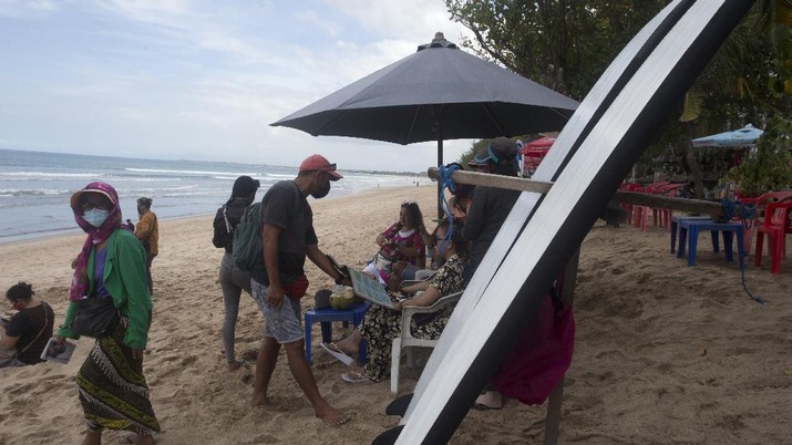 Aktivitas di pantai Kuta di Bali, Beach vendors wait for customers at Kuta beach in Bali, Indonesia, Thursday, Oct. 14, 2021. The Indonesian resort island of Bali welcomed international travelers to its shops and white-sand beaches for the first time in more than a year Thursday - if they're vaccinated, test negative, hail from certain countries, quarantine and heed restrictions in public. (AP Photo/Firdia Lisnawati)