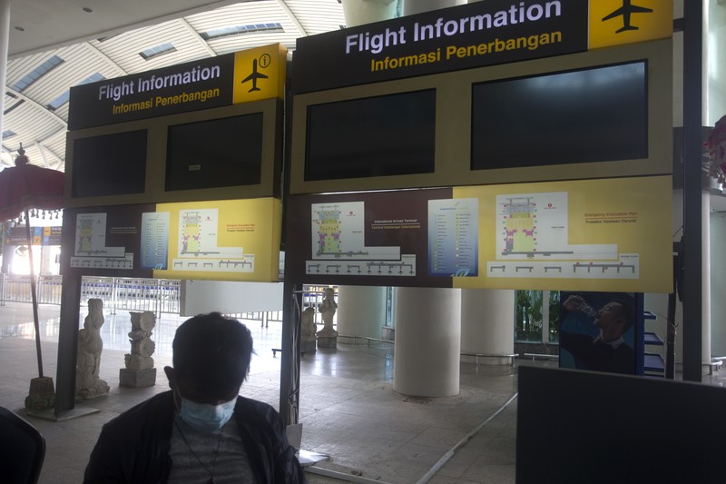 An airport worker marks queue line for the reopening of International Ngurah Rai Airport in Bali, Indonesia, Thursday, Oct. 14, 2021. The Indonesian resort island of Bali welcomed international travelers to its shops and white-sand beaches for the first time in more than a year Thursday - if they're vaccinated, test negative, hail from certain countries, quarantine and heed restrictions in public. (AP Photo/Firdia Lisnawati)