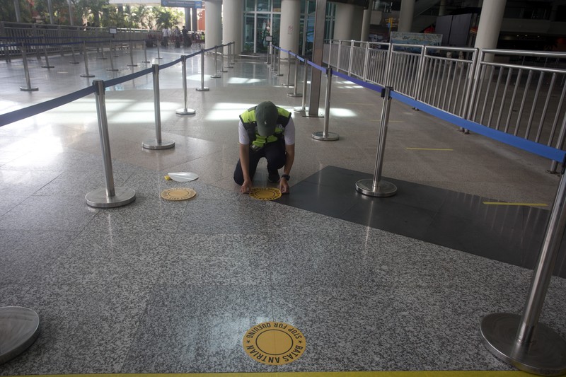 Bandara Internasional Ngurah Rai di Bali Bersiap Sambut Turis An airport worker marks queue line for the reopening of International Ngurah Rai Airport in Bali, Indonesia, Thursday, Oct. 14, 2021. The Indonesian resort island of Bali welcomed international travelers to its shops and white-sand beaches for the first time in more than a year Thursday - if they're vaccinated, test negative, hail from certain countries, quarantine and heed restrictions in public. (AP Photo/Firdia Lisnawati)