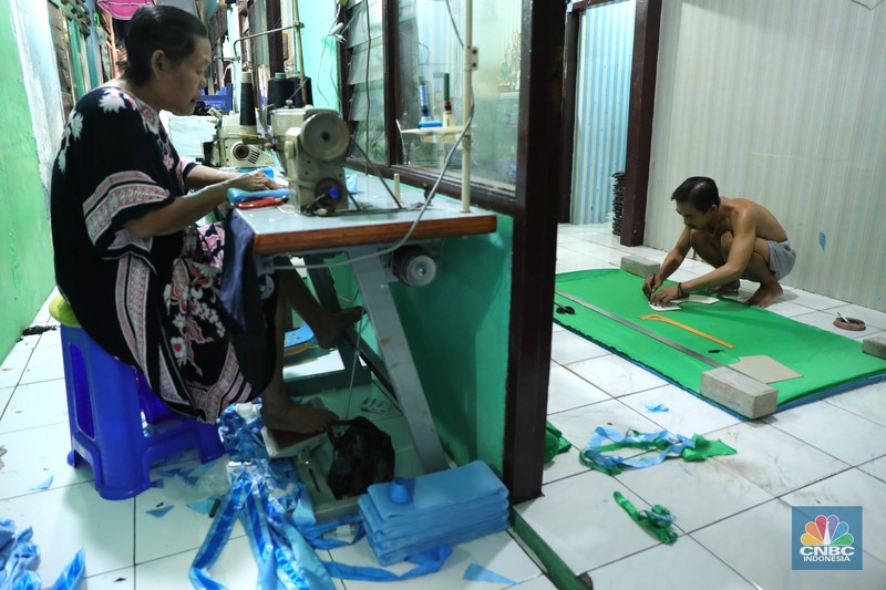 Pekerja menyelesaikan pembuatan baju wisuda (toga) di  kawasan Jakarta, Kamis (14/10/2021). Soleha (67) bisnis pembuatan baju toga sudah berjalan selama 28 tahun dan pandemi ini efeknya sangat luar biasa menurutnya. 

