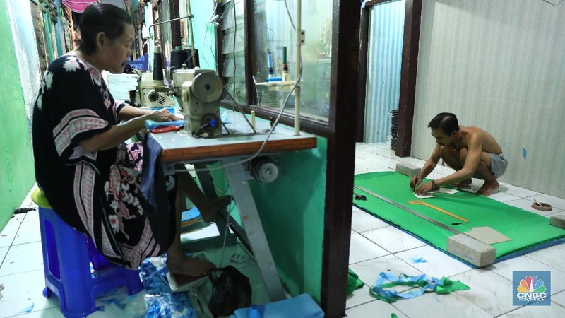 Pekerja menyelesaikan pembuatan baju wisuda (toga) di  kawasan Jakarta, Kamis (14/10/2021). Soleha (67) bisnis pembuatan baju toga sudah berjalan selama 28 tahun dan pandemi ini efeknya sangat luar biasa menurutnya. 

