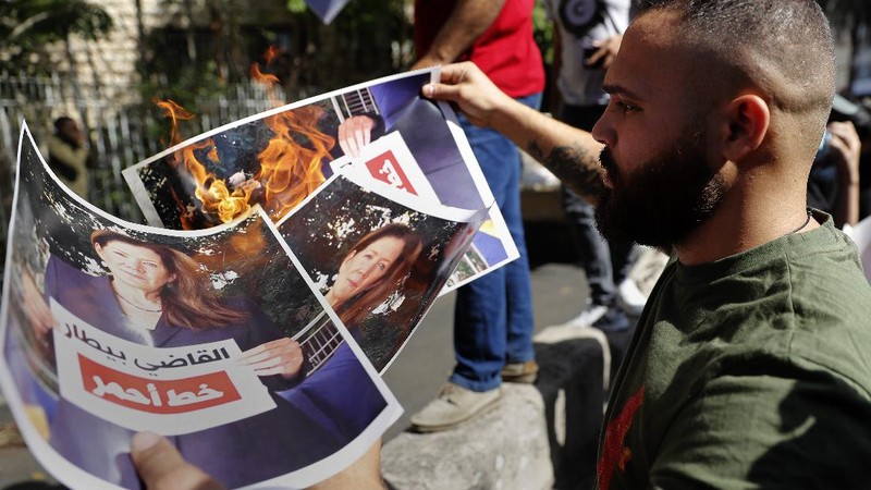 A supporter of the Shiite Hezbollah and Amal groups burns posters that show the U.S. Ambassador to Lebanon Dorothy Shea, and Arabic that reads: 