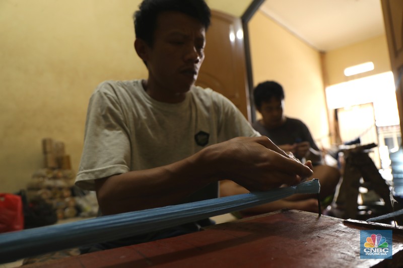 Pekerja menyelesaikan pembuatan baju wisuda (toga) di  kawasan Jakarta, Kamis (14/10/2021). Soleha (67) bisnis pembuatan baju toga sudah berjalan selama 28 tahun dan pandemi ini efeknya sangat luar biasa menurutnya. 

