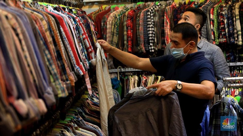 Pengunjung mencari pakaian second di Pasar Senen, Jumat, 15/10. Tren thrifting atau buru pakaian impor yang masih layak pakai berlanjut usai PPKM ketat akibat Corona mereda. Pasar Senen, Jakarta Pusat, merupakan salah satu tujuan yang paling banyak dipilih untuk thrift shop. Penampilan pasar yang semakin nyaman dan modern berkat peremajaan dan dibangun kembali pasca kebakaran pada April 2014 dan Januari 2017 lalu itu, membuat pengunjung betah berbelanja. Pengunjungnya mayoritas kalangan anak muda yang tampil gaya tanpa mengeluarkan banyak biaya, atau mereka yang mencari pakaian unik, branded dan tidak pasaran. Selain baju disini juga menjual sepatu branded second dan aksesoris lain. Harga yang dijual dari Rp20.000 hinggal Rp150 ribu bisa ditawar.  (CNBC Indonesia/ Muhammad Sabki)