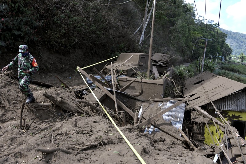 Indonesia Earthquake A woman walks past houses by Lake Batur which were damaged by an earthquake-triggered landslide in Bangli, on the island of Bali, Indonesia, Saturday, Oct. 16, 2021. A few people were killed and another several were injured when a moderately strong earthquake and an aftershock hit the island early Saturday. (AP Photo/Dewa Raka)