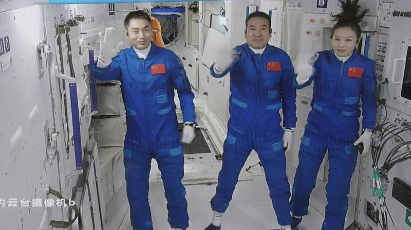 In this photo released by Xinhua News Agency, screen image captured at Beijing Aerospace Control Center in Beijing, China, Saturday, Oct. 16, 2021 shows three Chinese astronauts, from left, Ye Guangfu, Zhai Zhigang and Wang Yaping waving after entering the space station core module Tianhe. China's Shenzhou-13 spacecraft carrying three Chinese astronauts on Saturday docked at its space station, kicking off a record-setting six-month stay as the country moves toward completing the new orbiting outpost. Chinese characters,  left, read 