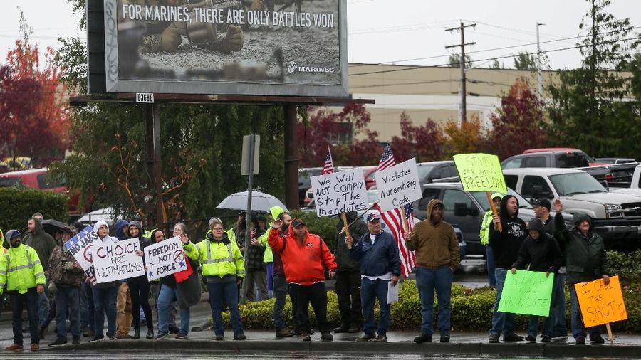 Boeing employees and others line the street with signs and American flags as they protest the company's coronavirus disease (COVID-19) vaccine mandate, outside the Boeing facility in Everett, Washington, October 15, 2021.  REUTERS/Lindsey Wasson