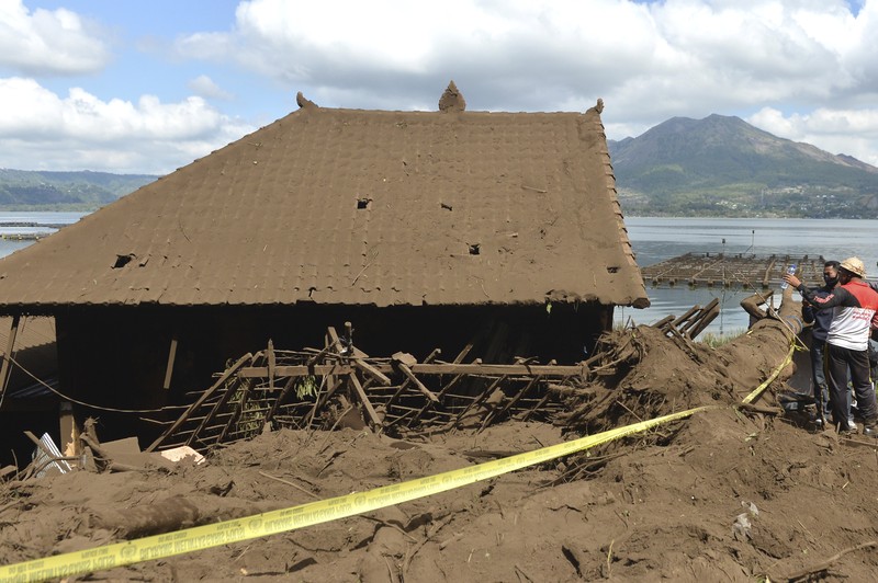 Indonesia Earthquake A woman walks past houses by Lake Batur which were damaged by an earthquake-triggered landslide in Bangli, on the island of Bali, Indonesia, Saturday, Oct. 16, 2021. A few people were killed and another several were injured when a moderately strong earthquake and an aftershock hit the island early Saturday. (AP Photo/Dewa Raka)