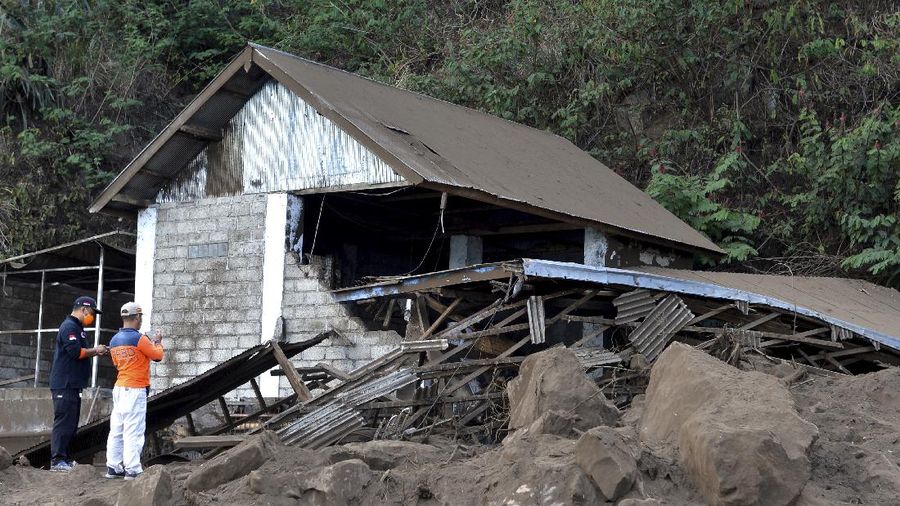 A woman walks past houses by Lake Batur which were damaged by an earthquake-triggered landslide in Bangli, on the island of Bali, Indonesia, Saturday, Oct. 16, 2021. A few people were killed and another several were injured when a moderately strong earthquake and an aftershock hit the island early Saturday. (AP Photo/Dewa Raka)