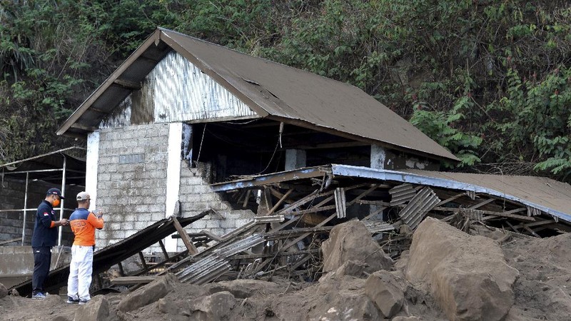 A woman walks past houses by Lake Batur which were damaged by an earthquake-triggered landslide in Bangli, on the island of Bali, Indonesia, Saturday, Oct. 16, 2021. A few people were killed and another several were injured when a moderately strong earthquake and an aftershock hit the island early Saturday. (AP Photo/Dewa Raka)