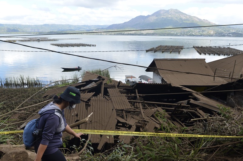 Indonesia Earthquake A woman walks past houses by Lake Batur which were damaged by an earthquake-triggered landslide in Bangli, on the island of Bali, Indonesia, Saturday, Oct. 16, 2021. A few people were killed and another several were injured when a moderately strong earthquake and an aftershock hit the island early Saturday. (AP Photo/Dewa Raka)