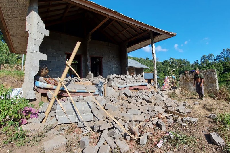 Indonesia Earthquake A woman walks past houses by Lake Batur which were damaged by an earthquake-triggered landslide in Bangli, on the island of Bali, Indonesia, Saturday, Oct. 16, 2021. A few people were killed and another several were injured when a moderately strong earthquake and an aftershock hit the island early Saturday. (AP Photo/Dewa Raka)