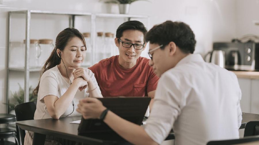asian chinese insurance agent explaining to his clients at their kitchen about the policies
