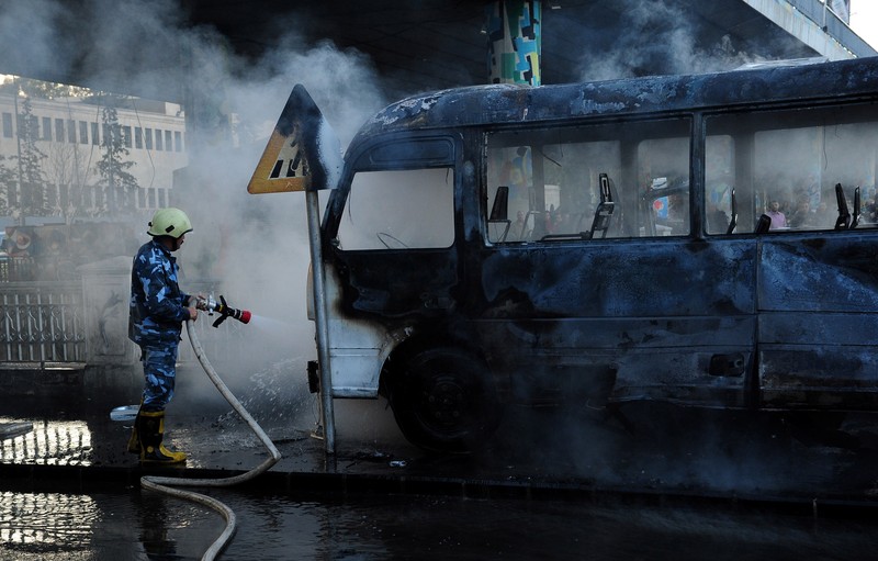 Ledakan bom bus militer di Suriah A civil defense member hoses down a bus at the site of a roadside bomb attack in central Damascus, Syria, in this handout released by SANA October 20, 2021. SANA/Handout via REUTERS ATTENTION EDITORS - THIS IMAGE WAS PROVIDED BY A THIRD PARTY. REUTERS IS UNABLE TO INDEPENDENTLY VERIFY THIS IMAGE.