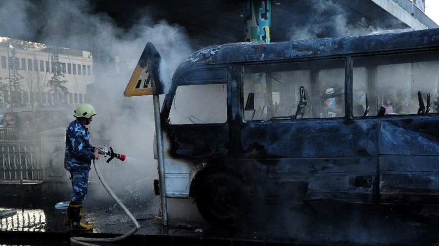 A civil defense member hoses down a bus at the site of a roadside bomb attack in central Damascus, Syria, in this handout released by SANA October 20, 2021. SANA/Handout via REUTERS ATTENTION EDITORS - THIS IMAGE WAS PROVIDED BY A THIRD PARTY.  REUTERS IS UNABLE TO INDEPENDENTLY VERIFY THIS IMAGE.