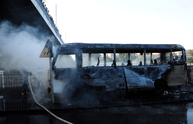 A civil defense member hoses down a bus at the site of a roadside bomb attack in central Damascus, Syria, in this handout released by SANA October 20, 2021. SANA/Handout via REUTERS ATTENTION EDITORS - THIS IMAGE WAS PROVIDED BY A THIRD PARTY.  REUTERS IS UNABLE TO INDEPENDENTLY VERIFY THIS IMAGE.