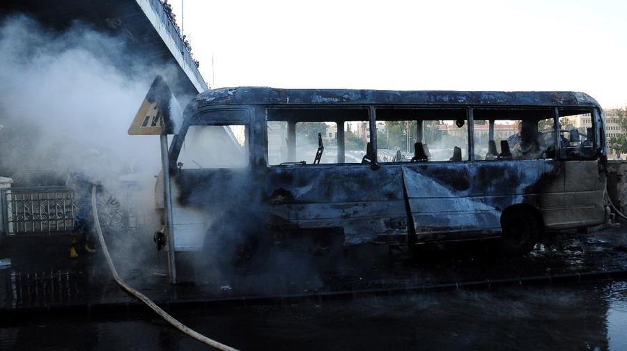 A civil defense member hoses down a bus at the site of a roadside bomb attack in central Damascus, Syria, in this handout released by SANA October 20, 2021. SANA/Handout via REUTERS ATTENTION EDITORS - THIS IMAGE WAS PROVIDED BY A THIRD PARTY.  REUTERS IS UNABLE TO INDEPENDENTLY VERIFY THIS IMAGE.