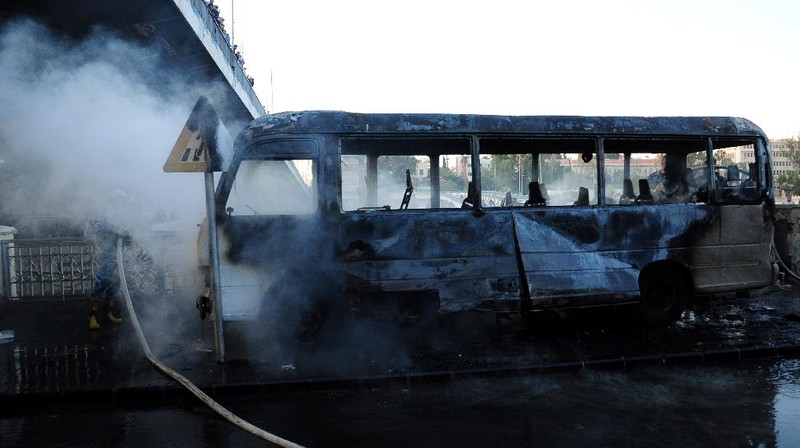 A civil defense member hoses down a bus at the site of a roadside bomb attack in central Damascus, Syria, in this handout released by SANA October 20, 2021. SANA/Handout via REUTERS ATTENTION EDITORS - THIS IMAGE WAS PROVIDED BY A THIRD PARTY.  REUTERS IS UNABLE TO INDEPENDENTLY VERIFY THIS IMAGE.