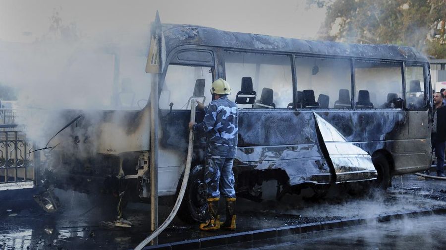 A civil defense member hoses down a bus at the site of a roadside bomb attack in central Damascus, Syria, in this handout released by SANA October 20, 2021. SANA/Handout via REUTERS ATTENTION EDITORS - THIS IMAGE WAS PROVIDED BY A THIRD PARTY.  REUTERS IS UNABLE TO INDEPENDENTLY VERIFY THIS IMAGE.