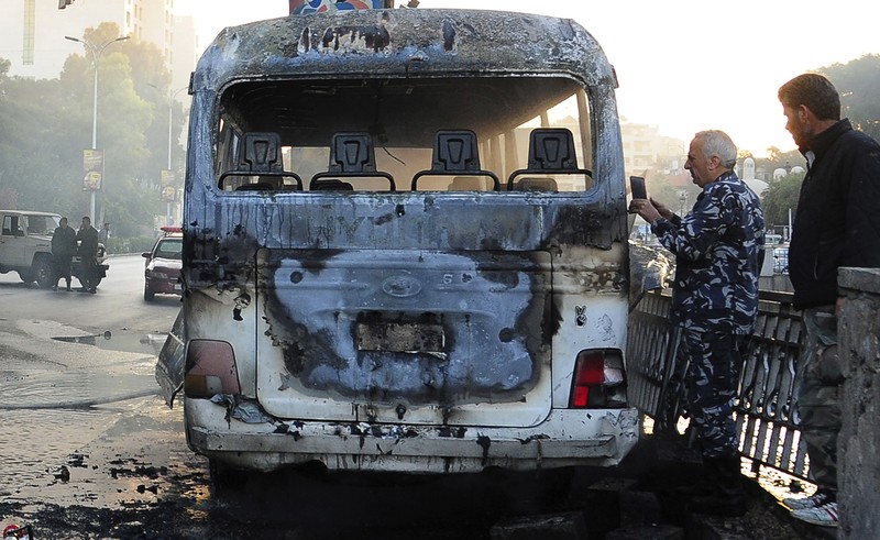 A civil defense member hoses down a bus at the site of a roadside bomb attack in central Damascus, Syria, in this handout released by SANA October 20, 2021. SANA/Handout via REUTERS ATTENTION EDITORS - THIS IMAGE WAS PROVIDED BY A THIRD PARTY.  REUTERS IS UNABLE TO INDEPENDENTLY VERIFY THIS IMAGE.