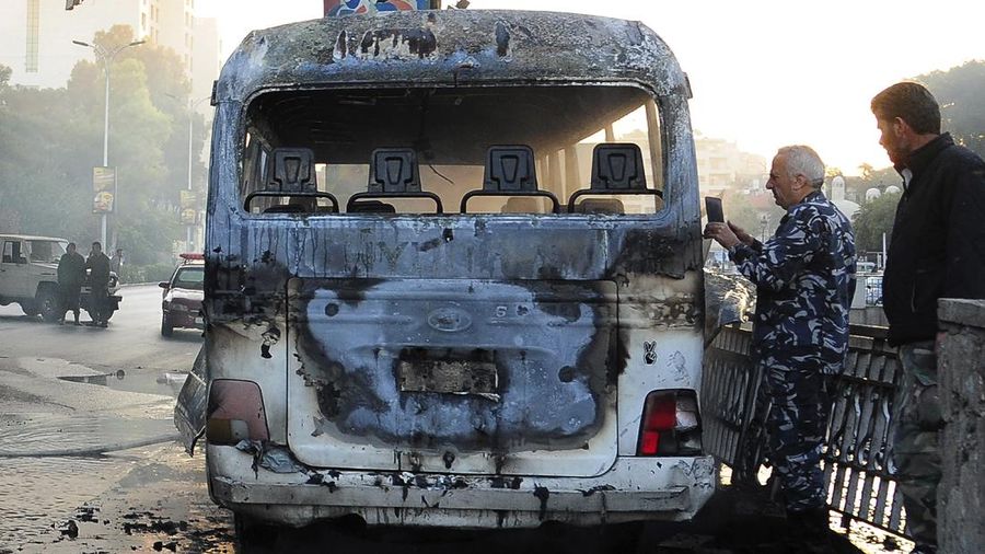 A civil defense member hoses down a bus at the site of a roadside bomb attack in central Damascus, Syria, in this handout released by SANA October 20, 2021. SANA/Handout via REUTERS ATTENTION EDITORS - THIS IMAGE WAS PROVIDED BY A THIRD PARTY.  REUTERS IS UNABLE TO INDEPENDENTLY VERIFY THIS IMAGE.