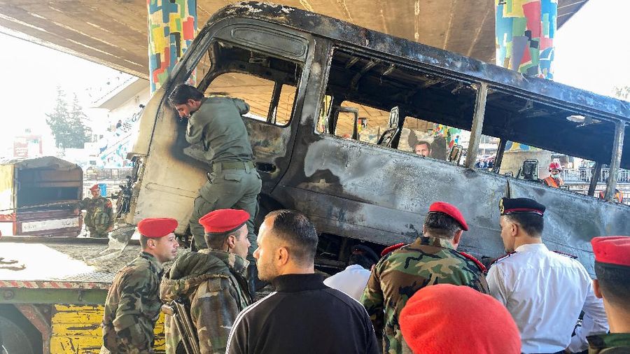 A civil defense member hoses down a bus at the site of a roadside bomb attack in central Damascus, Syria, in this handout released by SANA October 20, 2021. SANA/Handout via REUTERS ATTENTION EDITORS - THIS IMAGE WAS PROVIDED BY A THIRD PARTY.  REUTERS IS UNABLE TO INDEPENDENTLY VERIFY THIS IMAGE.