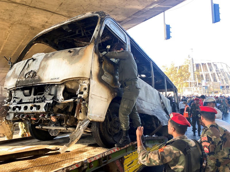 A civil defense member hoses down a bus at the site of a roadside bomb attack in central Damascus, Syria, in this handout released by SANA October 20, 2021. SANA/Handout via REUTERS ATTENTION EDITORS - THIS IMAGE WAS PROVIDED BY A THIRD PARTY.  REUTERS IS UNABLE TO INDEPENDENTLY VERIFY THIS IMAGE.