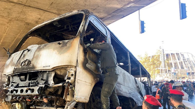 A civil defense member hoses down a bus at the site of a roadside bomb attack in central Damascus, Syria, in this handout released by SANA October 20, 2021. SANA/Handout via REUTERS ATTENTION EDITORS - THIS IMAGE WAS PROVIDED BY A THIRD PARTY.  REUTERS IS UNABLE TO INDEPENDENTLY VERIFY THIS IMAGE.