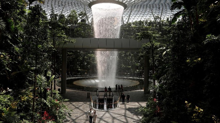 air terjun dalam ruangan di Bandara Jewel Changi di Singapura People walk past an indoor waterfall at Jewel Changi Airport in Singapore October 7, 2021. REUTERS/Edgar Su