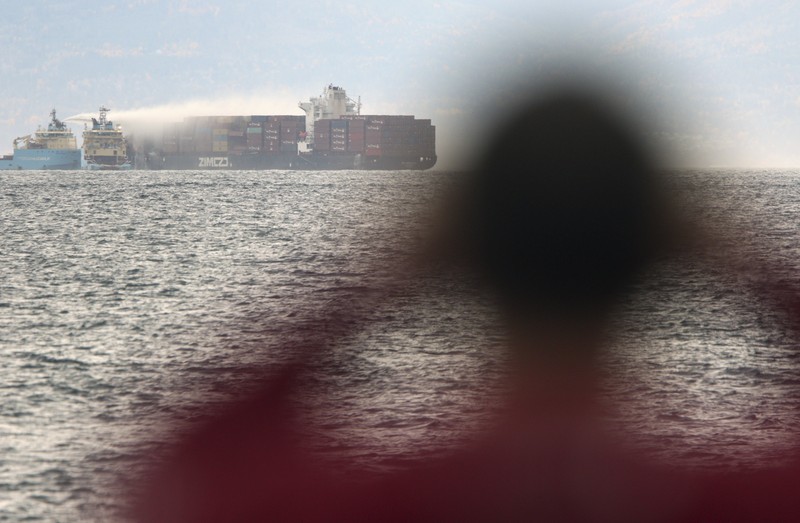 Canada Container Ship Fire Ships work to control a fire onboard the MV Zim Kingston about 8 kilometers (5 miles) from the shore in Victoria, British Columbia, Canaeda, on Sunday, Oct. 24, 2021. The container ship caught fire on Saturday and 16 crew members were evacuated and brought to Ogden Point Pier. (Chad Hipolito/The Canadian Press via AP)