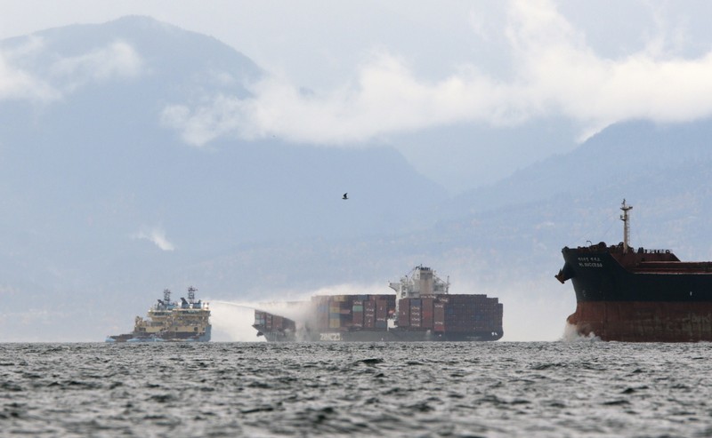 Canada Container Ship Fire Ships work to control a fire onboard the MV Zim Kingston about 8 kilometers (5 miles) from the shore in Victoria, British Columbia, Canaeda, on Sunday, Oct. 24, 2021. The container ship caught fire on Saturday and 16 crew members were evacuated and brought to Ogden Point Pier. (Chad Hipolito/The Canadian Press via AP)