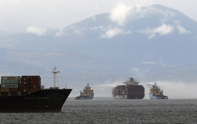 Ships work to control a fire onboard the MV Zim Kingston about 8 kilometers (5 miles) from the shore in Victoria, British Columbia, Canaeda, on Sunday, Oct. 24, 2021. The container ship caught fire on Saturday and 16 crew members were evacuated and brought to Ogden Point Pier. (Chad Hipolito/The Canadian Press via AP)