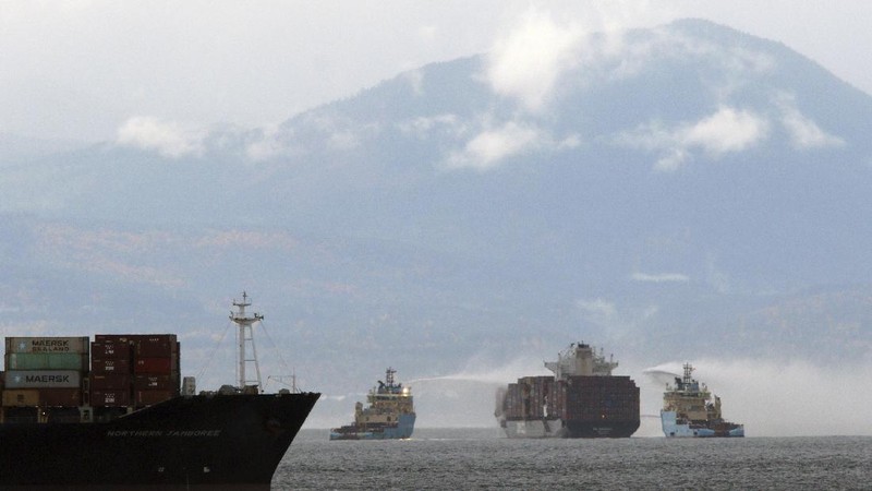 Ships work to control a fire onboard the MV Zim Kingston about 8 kilometers (5 miles) from the shore in Victoria, British Columbia, Canaeda, on Sunday, Oct. 24, 2021. The container ship caught fire on Saturday and 16 crew members were evacuated and brought to Ogden Point Pier. (Chad Hipolito/The Canadian Press via AP)