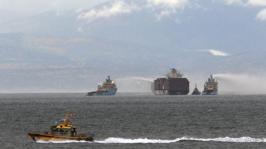 Ships work to control a fire onboard the MV Zim Kingston about 8 kilometers (5 miles) from the shore in Victoria, British Columbia, Canaeda, on Sunday, Oct. 24, 2021. The container ship caught fire on Saturday and 16 crew members were evacuated and brought to Ogden Point Pier. (Chad Hipolito/The Canadian Press via AP)