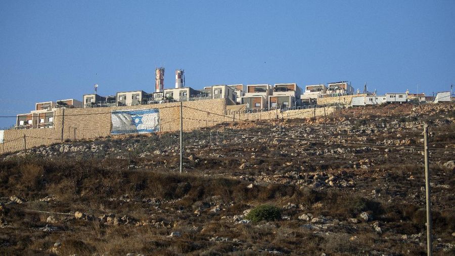 An Israeli flag is painted on the surrounding wall of the West Bank Jewish settlement of Migdalim near the Palestinian town of Nablus, Monday, Oct. 25, 2021. Israel is expected to move forward with thousands of new homes for Jewish settlers in the West Bank this week, a settlement watchdog group said Sunday. (AP Photo/Ariel Schalit)